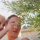 Happy Young Mom Hold Little Child in Her Arms and Showing Olive Tree in the Garden - VideoHive Item for Sale