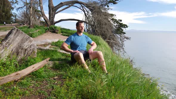 A man sitting down into a meditation pose to practice mindfulness and relieve stress after a workout