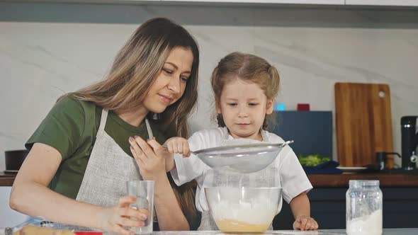 Mother Helps Daughter Sift Flour with Sieve Cooking Together