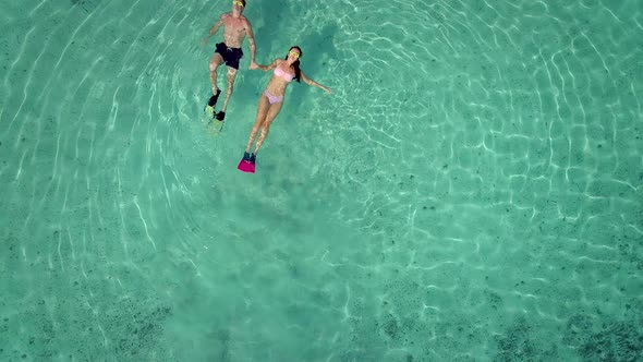 Aerial view of man and woman with masks and flippers swimming on their backs.