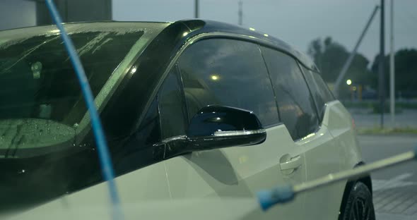 Woman with a Hose with Water in Her Hands Washes the Car