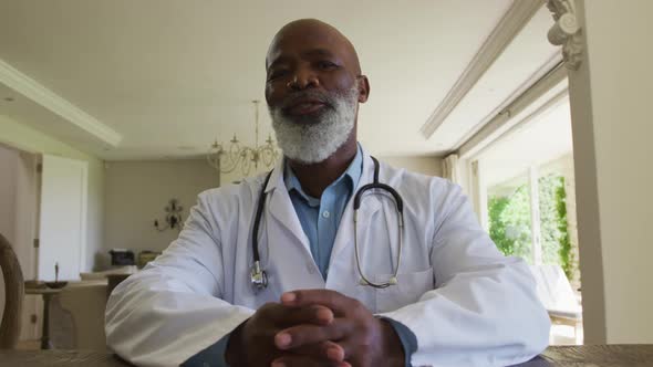 Portrait of african american senior male doctor talking looking at the camera at home