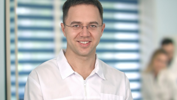 Male doctor in glasses smiling at camera while medical