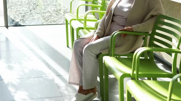 Thoughtful senior woman sitting on chair in lobby