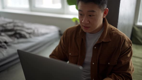 Confident Asian man wearing casual cloth working on laptop