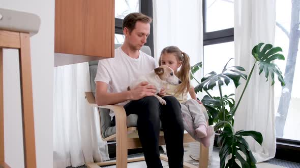 Little Girl and Father Cuddle Jack Russel Terrier at Home