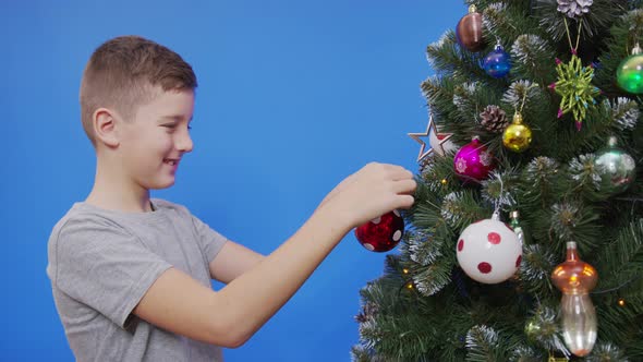 Happy Little Boy Decorating Christmas Tree with Balls