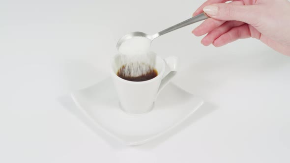 Putting sugar into the coffee and stirring it