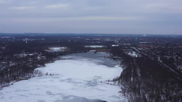 An aerial view from a drone, over a long lake during sunrise on a cloudy morning. The camera truck r
