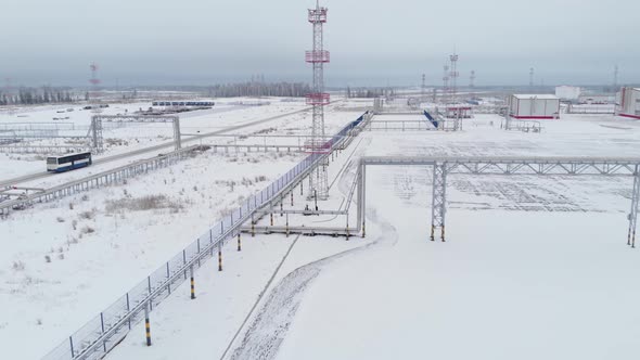 The Bus Drives Along the Road in Snowy Siberia the Drone Flies After It Past Searchlight Towers and