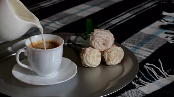 Pouring milk from milkman in white cup with hot coffee