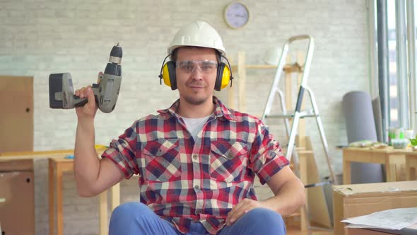 Portrait Young Disabled Man in a Wheelchair in a Helmet and with an Electric Drill in His Hand