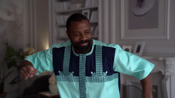 A Handsome African-American Man Celebrates Success While Sitting at Home in a Bright Office. A