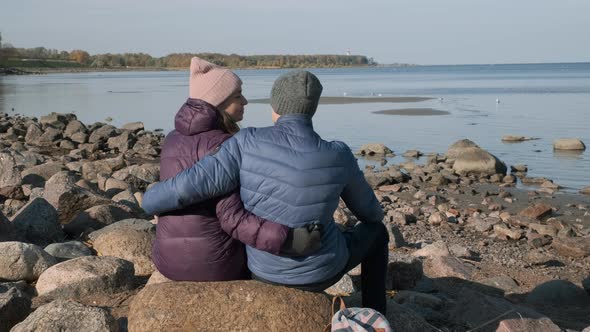 Romantic Couple Hugging on Stone Coast in Autumn