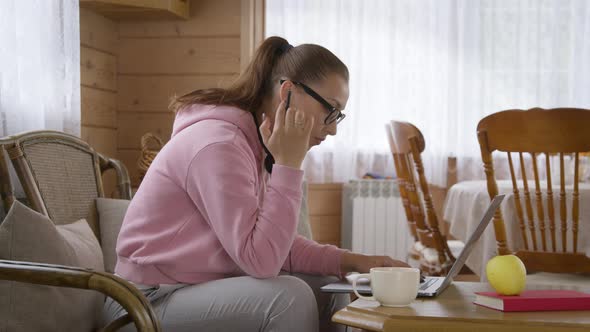 Woman in Hoodie Conducts Business From Home Using a Laptop During Coronavirus