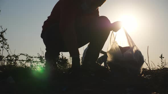 Close Up of Little Male Kid in Gloves Collect Trash in Bag Saving Nature at Countryside