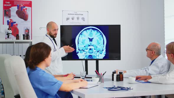 Qualified Bearded Head Doctor Explaining Brain Structure Using Monitor