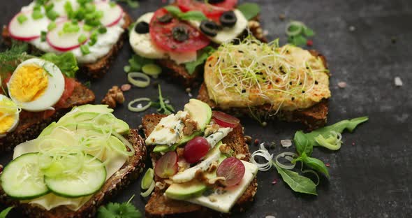 Variety of Healthy Fresh Sandwiches with Different Vegetables, Herbs and Ingredients on Dark Table