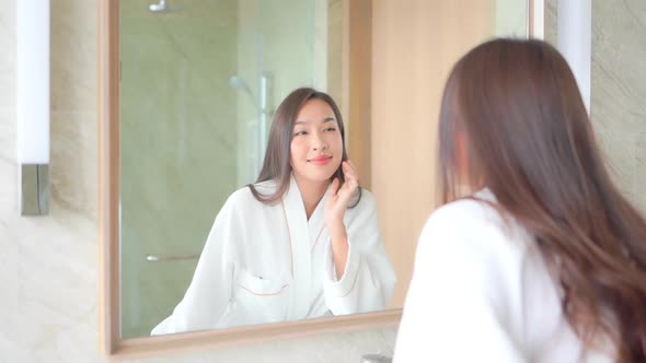 Young asian woman check her face on mirror