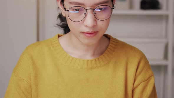 Asian woman wearing glasses using a laptop searching on the internet and shopping online.