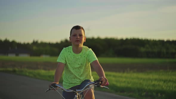 Caucasian Teenage Boy Rides a Bicycle in the Park