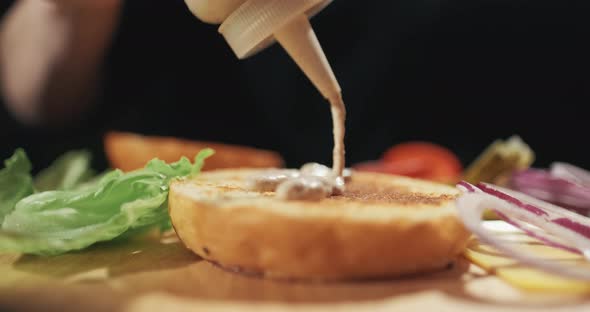 Chef Preparing the Burger. Close Up - Hand of Man Smears Sauce Fried Burger for a Hamburger. Slow