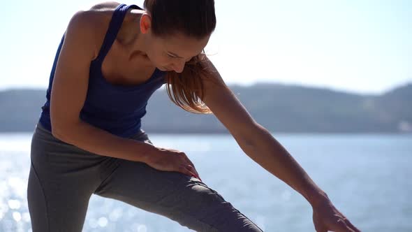 Sporty Girl Stretching Leg at Riverside