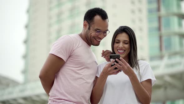 Smiling Friends Looking at Smartphone and Laughing