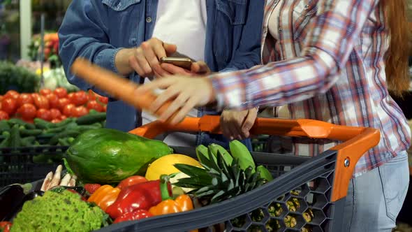 Couple Sorts Out Vegetables and Fruits in Grocery Cart