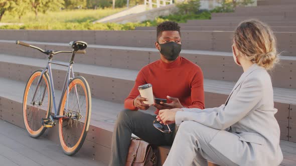 Interracial Business Couple in Face Masks Chatting Outdoors