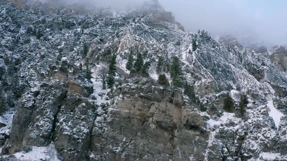 Flying over cliffs covered in snow viewing the rocky terrain