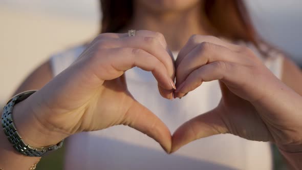 Cropped Shot of Young Woman Making Heart Shape with Hands