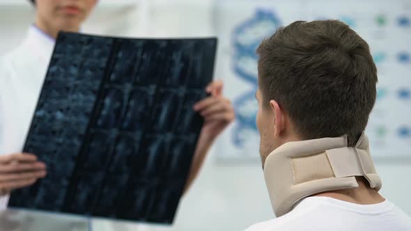Doctor Informing Man in Foam Cervical Collar Negative X-Ray Examination Result