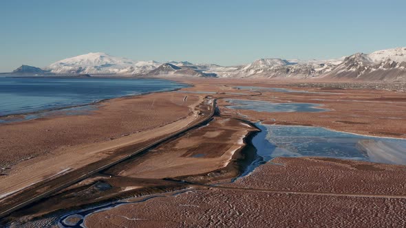 Drone Over Frozen Pools Of Water Towards Snow Covered Mountains