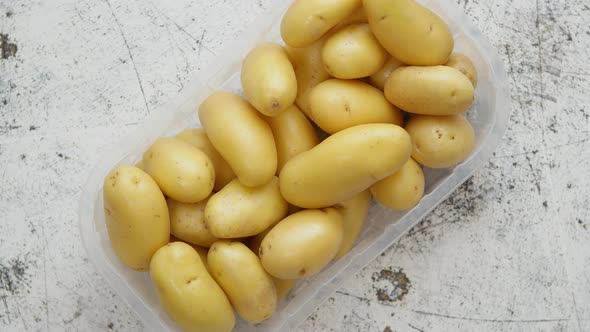 Fresh Young Potatoes in Plastic Basket Placed on Scatched Rusty White Background