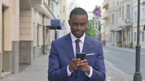 Walking African Businessman Using Smartphone