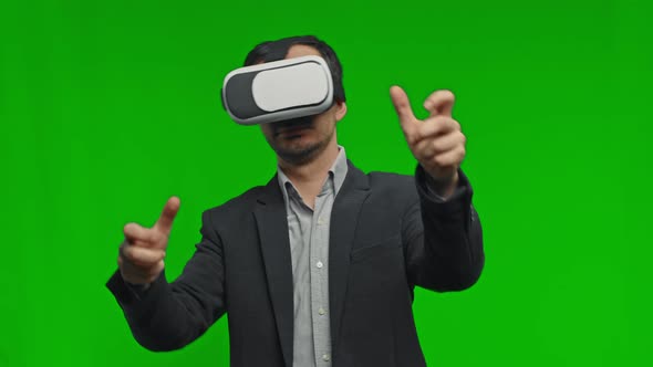 Amazed Man Using VR Headset Glasses Touching and Interacting with Virtual Reality World on Green