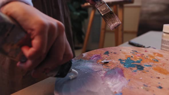 Art Studio Young Woman Artist Mixing Light Purple Color on the Palette and Applying It on the Canvas