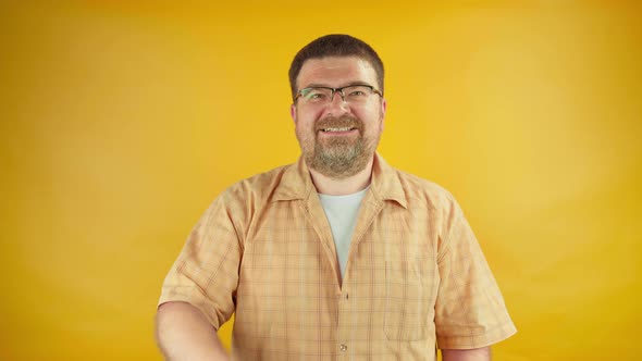 Bearded man in eyeglasses showing thumbs-up and smiling on camera, like, recommendation