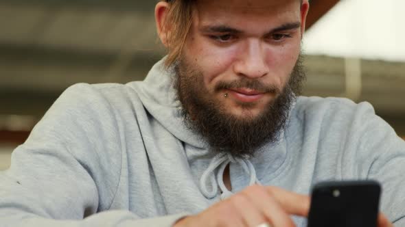 BMX rider using smartphone in an empty warehouse