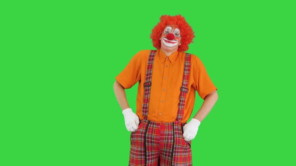 Clown Wearing a Red Nose Holding His Hands in Pockets While Looking Into the Camera on a Green