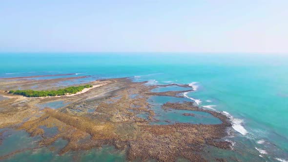 Scenic and empty rocky Island with small green bush area in the middle. Surrounded by blue ocean in