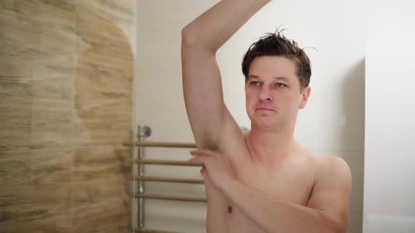 Man Using Deodorant Under His Arms in the Bathroom