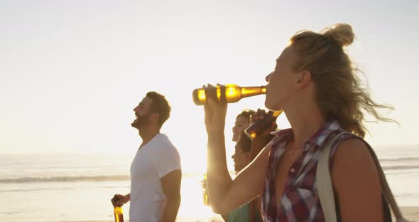 Young adult friends walking on a beach at sunset 4k