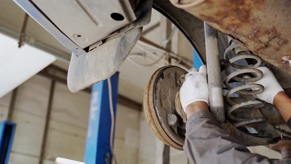 Hands of a Worker in White Gloves Adjust the Mechanism of Automobile Drum Brakes