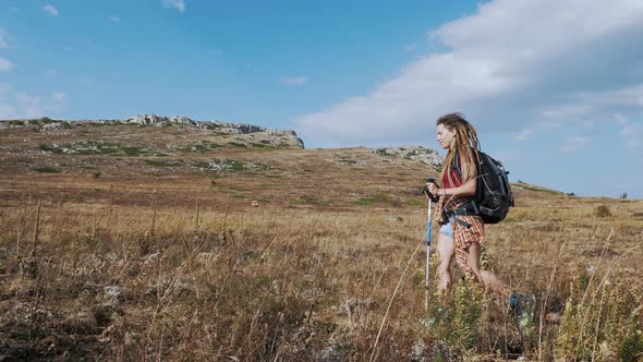 Girl with Backpack and Poles Going Through Steppe