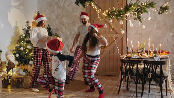 Family in Pajamas Dancing Cheerfully at Home on Christmas