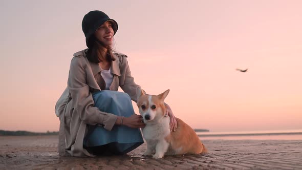 Woman Strokes Dog and Sits on Sea Beach During Evening Sunset Outdoors Spbi