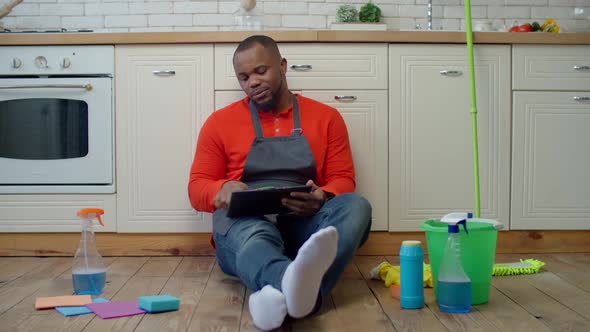 Tired Man Browsing Online on Tablet Pc After Cleanup