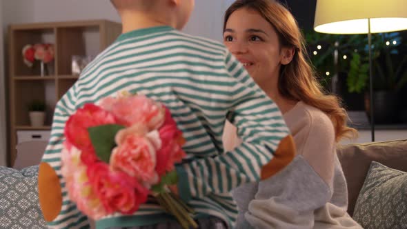 Smiling Little Son Gives Flowers To Mother at Home